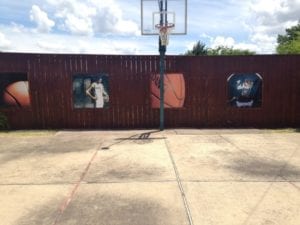Four basketball themed banners installed on a fence surrounding a basketball court