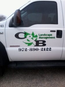 Door of white work truck with black and green decals for landscape management company